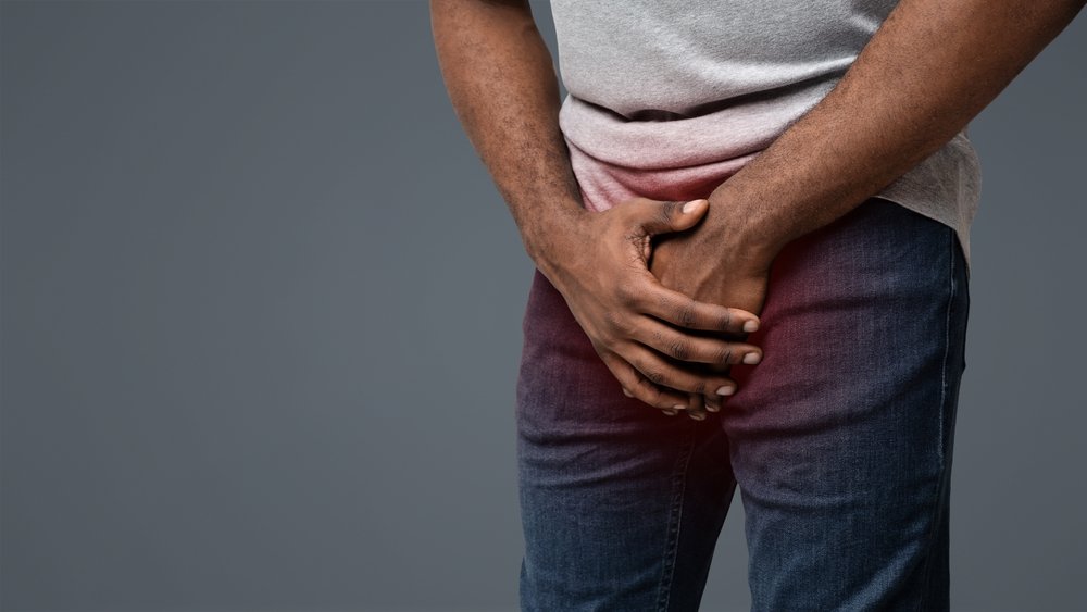 Man clutching his groin area with both hands over his jeans, indicating severe pelvic or testicular pain and possible urinary or urologic problem that needs evaluation by a urologist in Indore such as Dr. Pritesh Shrimali, best urologist in Indore.​