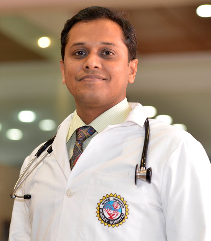 Male doctor in a white coat with a stethoscope around his neck standing in a hospital corridor, representing an experienced urologist providing specialised kidney and urinary care in Indore.