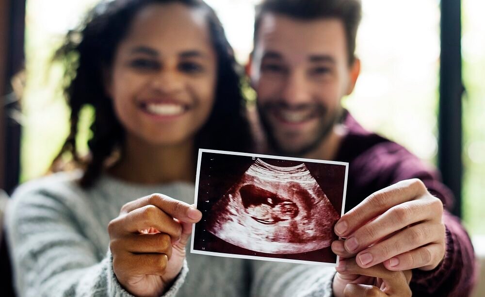 Happy couple holding an ultrasound scan image of their baby, symbolising successful pregnancy after fertility and urologist treatment in Indore with Dr. Pritesh Shrimali, best urologist in Indore.